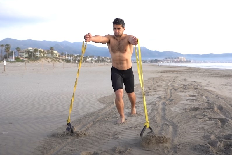 Guy practicing grip training on a sandy beach